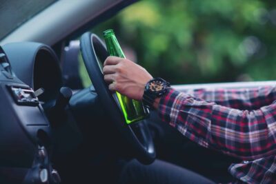 Hansome man holding beer bottle while driving a car