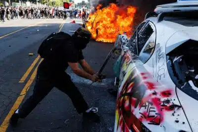 This picture taken on June 8, 2025 shows a protestor shattering the window of a Waymo vehicle during a demonstration following federal immigration operations in Los Angeles. Demonstrators torched cars and scuffled with security forces in Los Angeles on June 8, as police kept protestors away from the National Guard troops President Donald Trump sent to the streets of the second biggest US city. (Photo by BLAKE FAGAN / AFP)