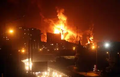 TEHRAN (IRAN(Islamic Republic Of)), 15/06/2025.- People drive as fire and smoke rise from Tehrans oil warehouse in Tehran, Iran, 15 June 2024. Israel continues strikes on Irans nuclear program and energy facilities.  (Teherán) EFE/EPA/ABEDIN TAHERKENAREH