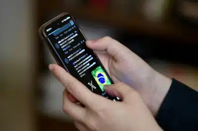 (FILES) A Brazilian user of the social network X, formerly Twitter, browses posts on a cell phone in Brasilia on August 31, 2024. Brazil's Supreme Court on September 19, 2024 ordered Elon Musk's X to suspend access to the social network, after service was restored despite a ban, or face a daily fine of over $900,000. (Photo by EVARISTO SA / AFP)