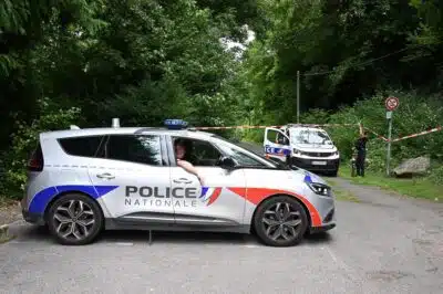 Police cars are parked in front of a cordoned-off area, near a sports field where a 32-year-old man was found dead with his throat slit and gutted, in Pont-de-Metz on August 4, 2025. The victim had stab wounds to the neck and back and has been found by a walker in a cross position, police told AFP. (Photo by Francois NASCIMBENI / AFP)